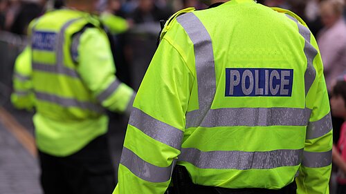 Photo of two police officers in hi-vis jackets from the back