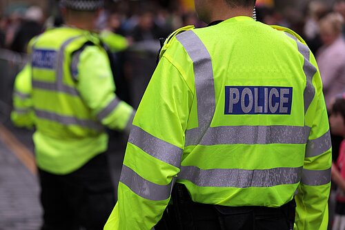Photo of two police officers in hi-vis jackets from the back